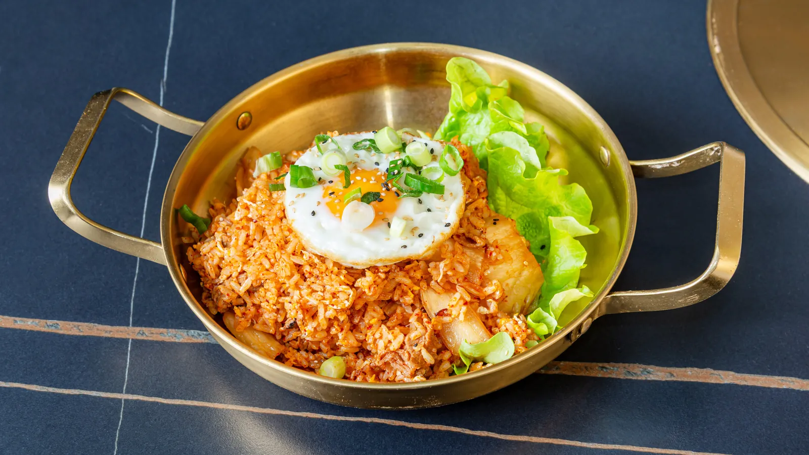 Riz sauté au kimchi avec un œuf au plat, dans une poêle dorée