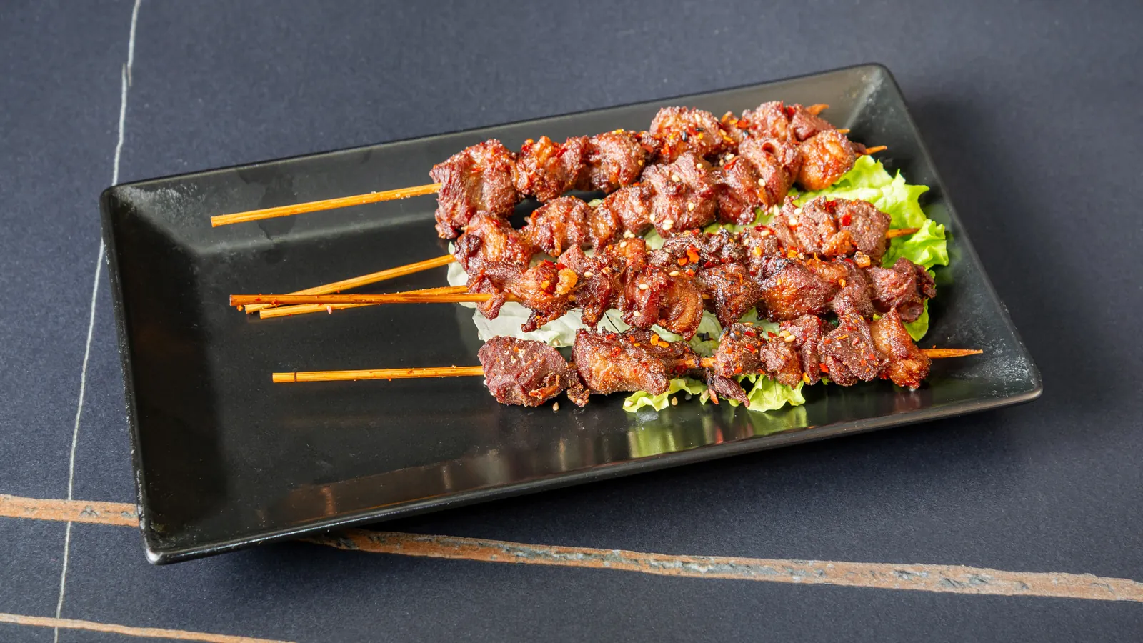 Brochettes de viande grillée sur un plat noir rectangulaire